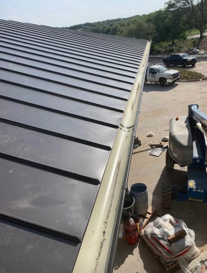 Standing seam panel and gutter detail on a metal roofing jobsite in Worth
